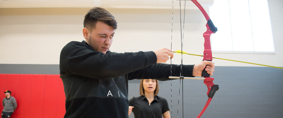 A Teacher education student shooting a bow and arrow.