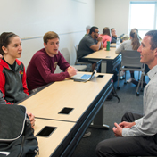 Students speaking to a professor in a classroom