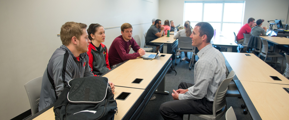 Students speaking to professor in a class room