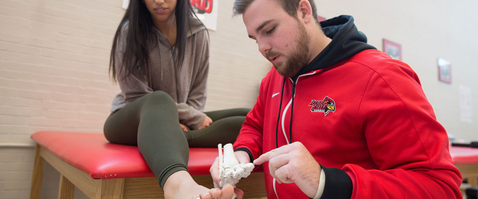 Graduate student explaining the bone structure of the foot to another student.