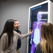 Three students observe an scan of human muscles.