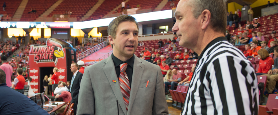 An I S U staff member speaking to a basketball referee in Redbird Arena.